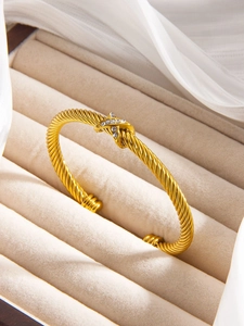 Macro detail of gold cable twisted bracelet with crisscross X motif and inlaid diamonds