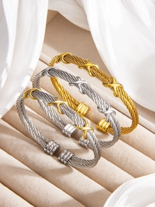 Detailed view of three twisted cable bracelets in gold and silver with X-shaped accents