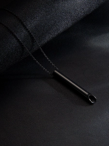Détail macro du pendentif sifflet de méditation noir sur fond de cuir texturé élégant