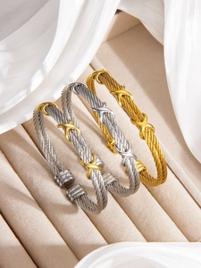 Detailed view of twisted cable cuff bracelets in gold and silver with X-shaped accents