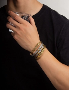 Close-up of twisted cable bracelets with gold and silver X-shaped metal decorative clasps