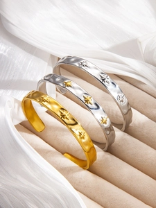 Close-up of three hammered cuff bracelets with star patterns on beige velvet and satin