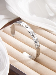 Macro detail of silver star embossed open bangle with hand-hammered texture finish
