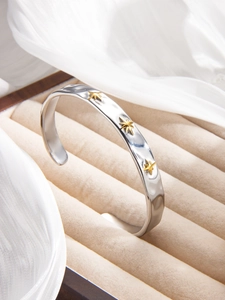 Detail of silver hammered texture cuff bangle with three golden stars on velvet display