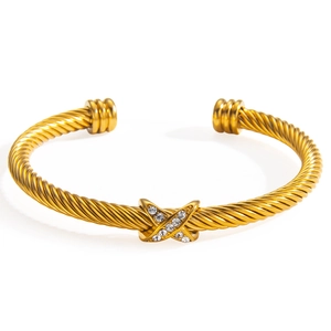 Gold cable twist bangle featuring an X-shaped charm with embedded sparkling crystals