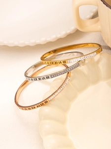 Detail of Roman numeral engraved bangles in gold, silver, and rose gold with square diamonds