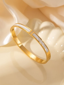 Close-up of golden titanium steel bangle with white shell inlay and zircon details