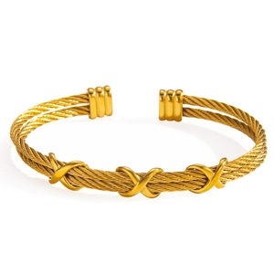 Gold twisted cable cuff bracelet with X-shaped polished metal accents on white background