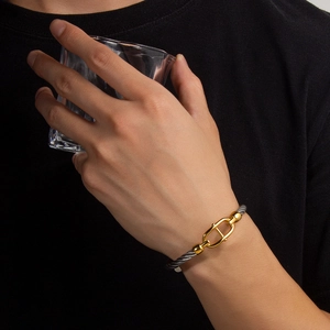 Macro detail of 18k gold plated nautical buckle and braided steel cable bracelet