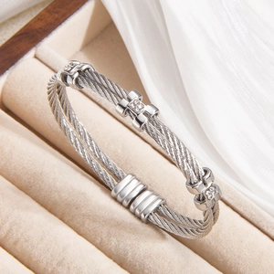 Silver twisted cable cuff bracelet with diamond-set H-shaped buckles on beige velvet