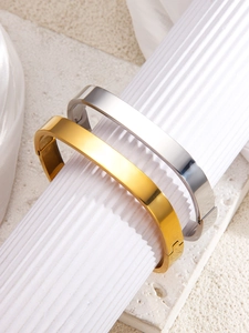 Polished gold and silver square bangle set displayed on a white aesthetic pedestal