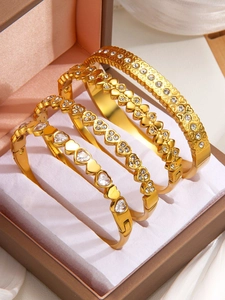 Macro detail of four gold heart-shaped bangles with crystals in a jewelry box