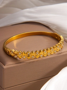 Detail of gold heart-shaped bracelet with inlaid diamonds and delicate side clasp