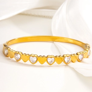 Elegant gold heart bracelet with alternating diamonds on a white silk background