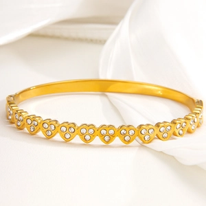 Polished gold heart-shaped titanium steel bracelet with sparkling zircons on white silk