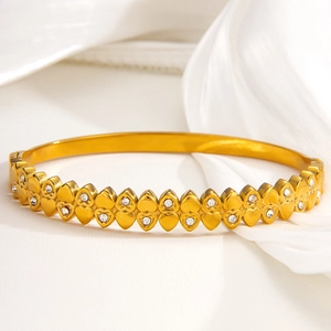 Luxurious gold heart-shaped bangle with sparkling diamond accents on soft satin background