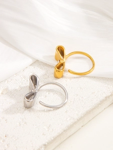 Detailansicht der Schleifenringe in Gold und Silber auf elegantem weißen Seidenhintergrund
