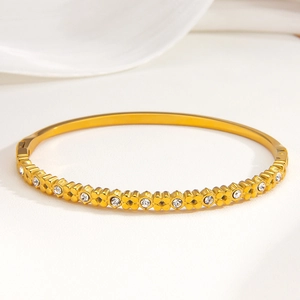 Poliertes Gold-Kleeblatt-Armband mit funkelnden Kristallen auf weißem Hintergrund
