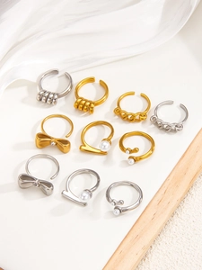 Detailed close-up of mixed pearl and bow rings set on a white silk background