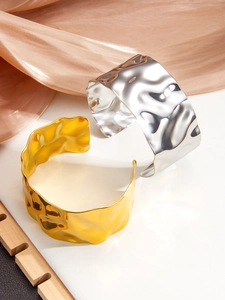 Detail of wide hammered metal cuffs in gold and silver finish on silk fabric
