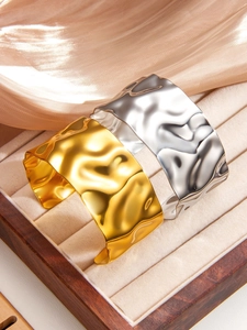 Detail of wide hammered texture 18k gold and silver bangles in a velvet jewelry box