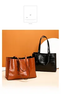 Detail view of large tote bags with crocodile pattern embossing and metal hardware