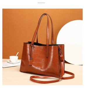 Detail view of crocodile pattern texture and metal D-ring on brown crossbody bag
