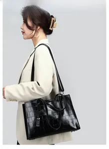 Detail of black crocodile texture tote bag with metallic buckles and twin top handles