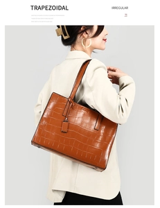 Detail of a brown crocodile pattern trapezoidal tote bag with elegant leather texture