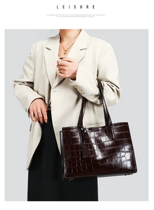 Detail of dark brown faux crocodile leather tote bag with glossy finish and top handles