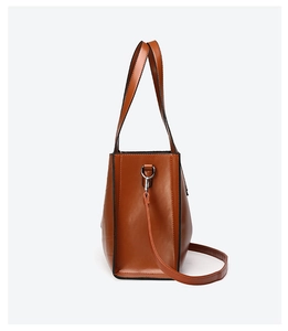 Detail view of the brown leather tote bag with adjustable strap and metal hardware