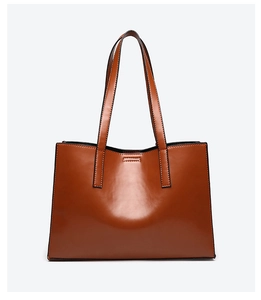 Front view of a minimalist brown leather tote bag with long straps and black edge paint