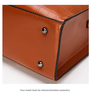 Detail of caramel crocodile embossed leather bag bottom with four silver metal rivets