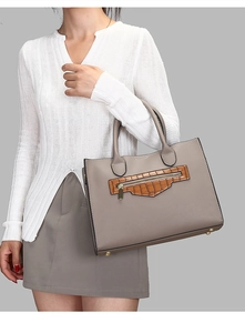 Detail of gray tote bag showing lychee texture, crocodile trim, and metal bottom feet