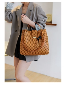 Close-up of retro brown leather tote bag with geometric patterns and tassel detail