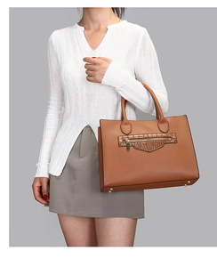 Detail of brown litchi grain leather tote bag with crocodile texture pocket and gold studs