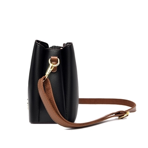 Sac seau en cuir grainé noir avec large bandoulière marron et détails dorés