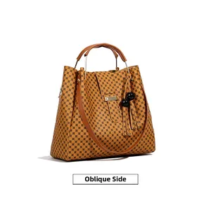 Oblique view of a yellow tote bag with black geometric grid and leather handles