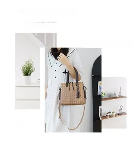 Detail of woven brown handbag with leather handles and decorative tassel ornament