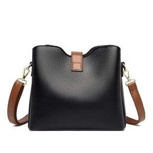 Sac seau en cuir grainé noir avec bandoulière marron et boucles dorées chic