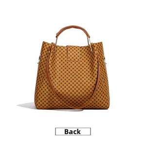 Back view of a vintage brown handbag with geometric patterns and leather handles