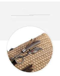 Detail of woven khaki handbag featuring a metal cat charm with brown tassel ornament