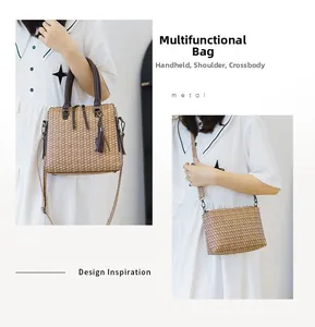 Detail of checkered woven handbag with dark cylindrical handles and tassel charm