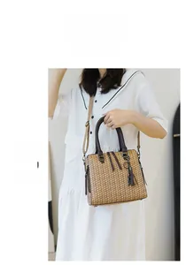 Brown woven texture handbag with dark top handles and fringe detail on a white dress model