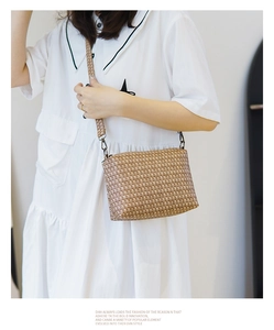 Detail of woven texture crossbody bag with bronze metal buckles and wide shoulder strap