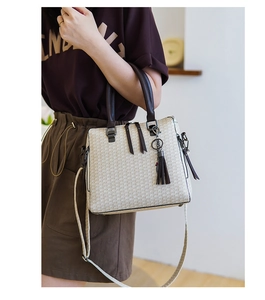 Close-up of beige woven texture and dark brown leather straps on an elegant handbag