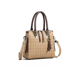 Detailed side view of woven beige tote bag with brown leather handles and decorative tassel