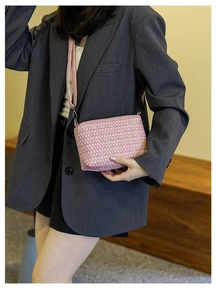 Detailed view of pink tweed woven crossbody bag with matching shoulder strap on a model