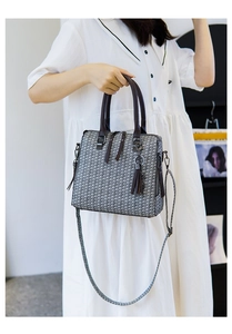 Detail of woven texture handbag with dark brown handles and elegant tassel pendant