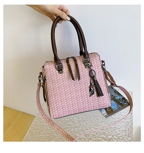 Pink tweed handbag with embossed texture, leather handles, and a cute black cat charm